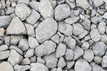 A close-up view of a pile of light grey, angular stones, commonly known as gravel or crushed rock.