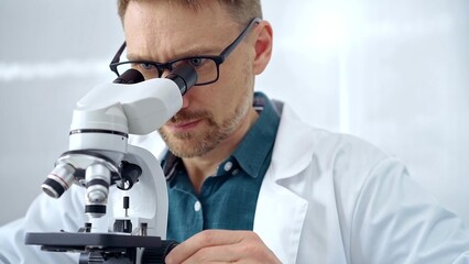 Man scientist with protective glasses using microscope in laboratory. Microbiology science concept