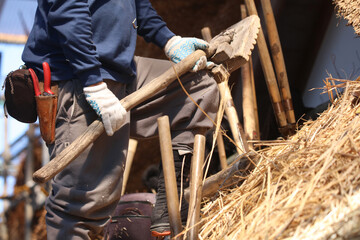 茅葺き屋根の茅を押し整える職人