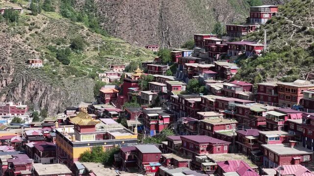 Aerial view of Larung Gar's clustered red and white buildings nestled against the rugged terrain, revealing a unique urban landscape, Garz&ecirc;, Sichuan, China.