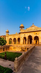 Obraz premium Sandstone edifice, arched colonnades, central dome, flanking towers, descends to a garden