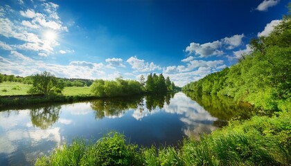 calm river reflects blue sky and clouds under bright sunlight near lush greenery