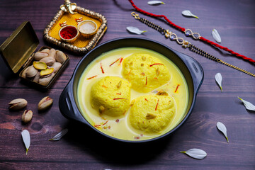 Delicious rasmalai served in a bowl, placed beside a decorative rakhi and a traditional roli chawal...
