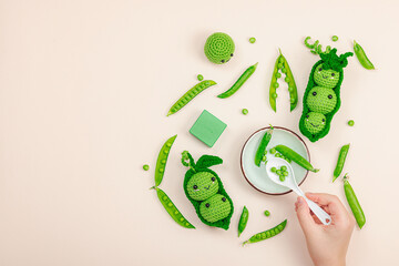 Child plays with handmade crochet pea pods and fresh green peas. Toy vegetables, eco craft