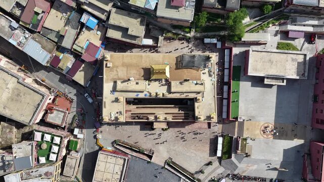 Aerial view of Dege Parkhang Printing house showcases architecture, with people gathered around the courtyard, Dege, Sichuan, China.