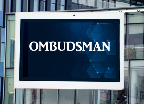 the word ombudsman on a digital tablet with office building in the background