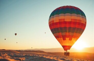 Obraz premium Colorful hot air balloon floating over desert landscape at sunrise