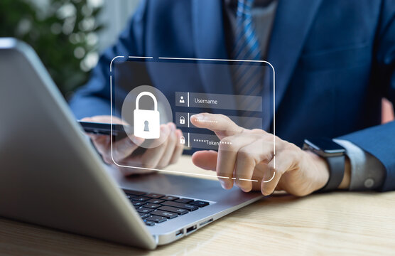 Businessman typing on keyboard enter username password and receive the token from mobile for system software registration on laptop in dark office cybersecurity and data protection technology concept.