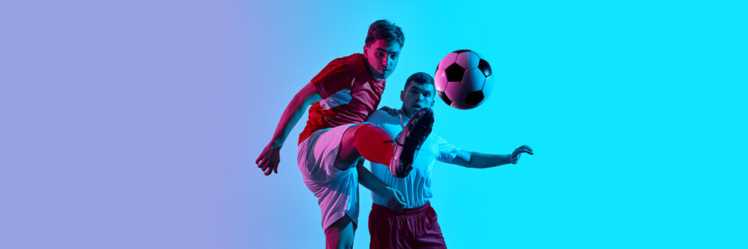 Dynamic soccer action between two players in vibrant blue and purple lighting with ball mid-air. Concept of modern sports, intense competition, skill, and fast-paced athletic performance. Banner - Powered by Adobe