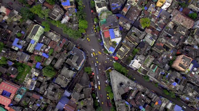  A top angle shot of cars, cabs and bikes moving on a busy street or crossroad junction in a congested part of the downtown Kolkata or Calcutta city, India surrounded by the century old buildings. 