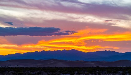 Vibrant sunset hues paint the sky above a silhouetted mountain range and desert landscape