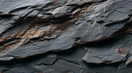 Textured slate stone surface with dark hues, showcasing natural formations and subtle earthy tones.