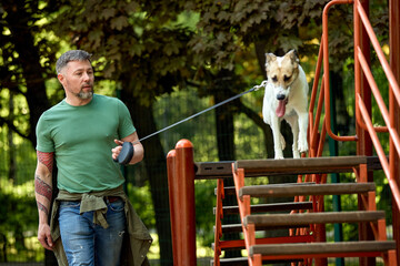 Man guiding his energetic dog on an obstacle course in the park