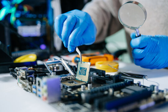 The technician is putting the CPU on the socket of the computer motherboard. electronic engineering electronic repair, electronics measuring