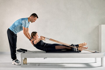 Professional instruction during a Pilates reformer session for improved strength and posture