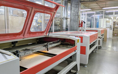 Laser cutter in modern industrial setting. Machine is open, revealing the bed where materials are cut