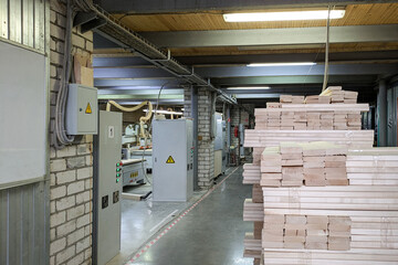 Industrial workshop with stacks of wooden planks in th foreground. Row of CNC machines and lines of...