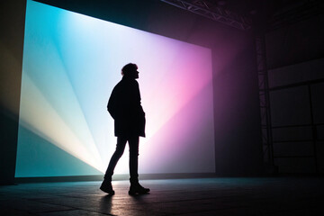 Silhouette of a person standing in front of a vibrant colorful light projection