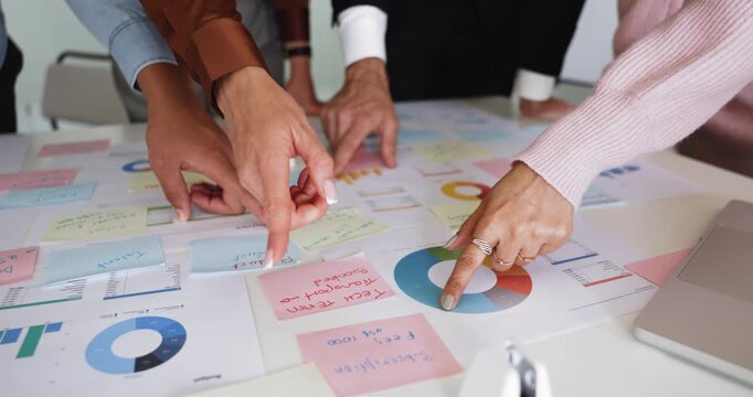 Hands of marketing agency staff analyzing heap of paper reports with diagrams on meeting table, pointing at analytic data, working on sales strategy, KPI, benchmark growth. Close up shot