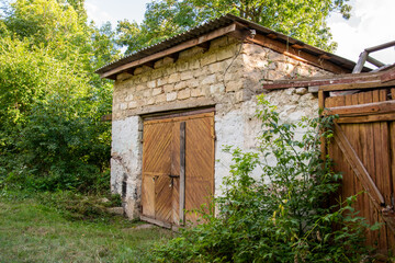 A small stone building with a wooden door in the middle of a field