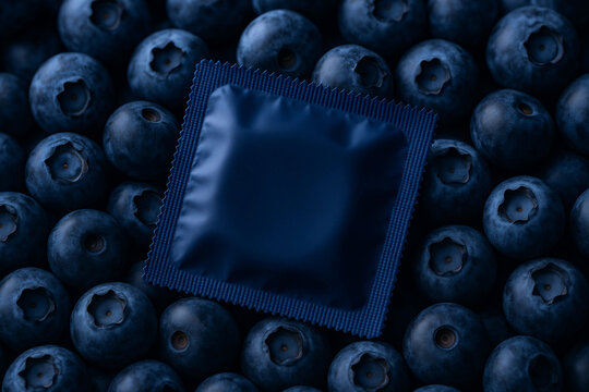 Modernes Kondom-Mockup in dunkelblauer Verpackung, liegend auf frischen Heidelbeeren, hochwertiges Produktdesign f&uuml;r Werbung.