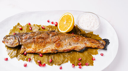 Grilled trout served on a platter with garnishes and dipping sauce