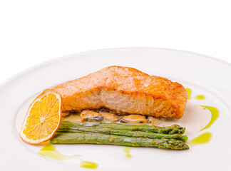 Salmon fillet with asparagus and citrus garnish served on a white plate