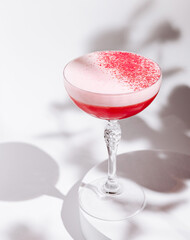 Elegant pink cocktail served in a crystal glass with frothy texture and garnish