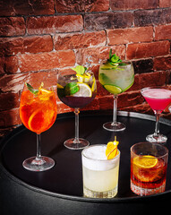 Colorful cocktails displayed on a circular table against a brick background