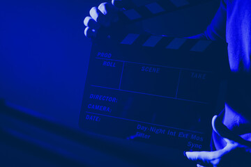 Film Crew Member Holding a Clapperboard in Dimly Lit Studio Environment