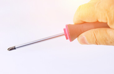 The hand is holding a screwdriver with an insulated handle. Close-up. Macro. 
