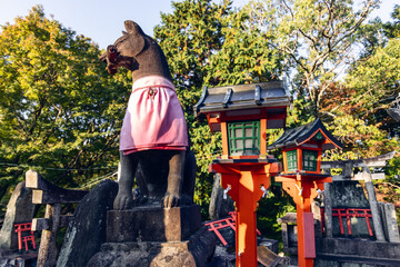 Sacred fox guardian overlooks stone altars and red lanterns near the summit of Mount Inari in...