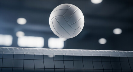 A volleyball hovering over a net in a dimly lit gymnasium with blurred lights in the background