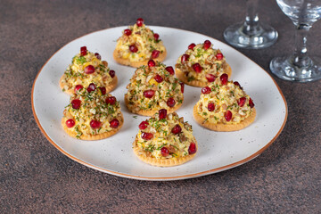 Appetizer on crackers of cheese, walnuts and pomegranate in the shape of Christmas trees