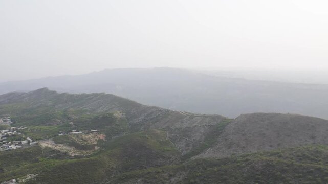 Aerial view of rocky ridges and sparse greenery in Kallar Kahar, Chakwal, under a hazy sky. Chakwal, Pakistan