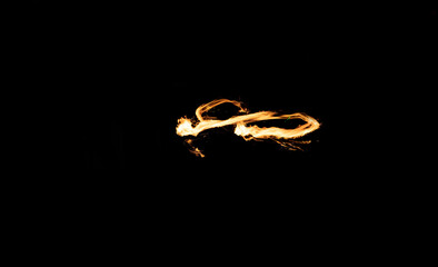 Abstract long-exposure photograph of fire trails forming a dynamic infinity loop pattern against a completely black background.