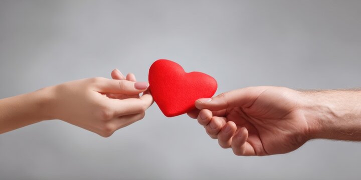 The hands exchanging a red heart symbolize love and connection between partners.