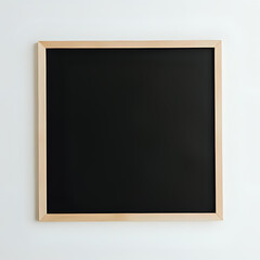 Blank black chalkboard with light wood frame against a white wall background