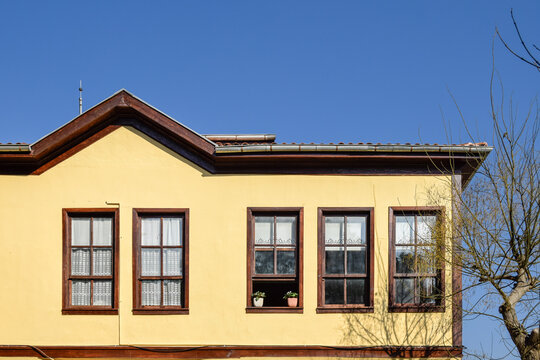 View of a yellow building with brown trim and windows against a clear blue sky, evoking a sense of warmth and architectural charm, Safranbolu, Karab&Atilde;&frac14;k, T&Atilde;&frac14;rkiye.