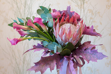 Vibrant floral arrangement featuring protea, calla lilies, and eucalyptus in soft lighting