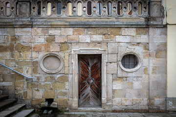 Old architectural structure featuring a wooden door and stone wall in a historical urban setting
