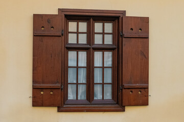 Wooden window with shutters and grid design on a beige wall in a historic building