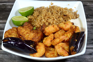 A plate of seafood of Fried Epinephelus fish fillet, Egyptian fish rice and Fried shrimps covered with flour and fried in deep oil, lemon and Pickled roast fried Aubergine eggplant