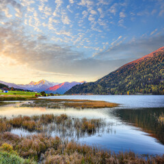 Gorgeous autumn view of Haidersee (Lago della Muta) lake with Ortler peak on background.
