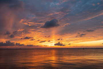 A breathtaking sunset over the tranquil sea with vibrant orange and yellow hues painting the sky and reflecting on the water.