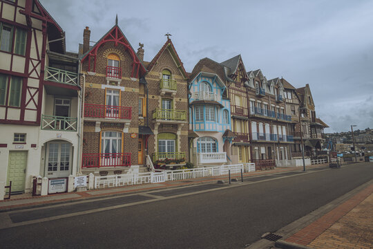 Fototapeta View of a row of vibrant, historic houses, each with unique architectural details and colorful facades, line a quiet street under a cloudy sky, Mers-les-Bains, Hauts-de-France, France.