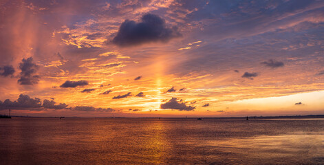 A breathtaking sunset over the tranquil sea with vibrant orange and yellow hues painting the sky and reflecting on the water.