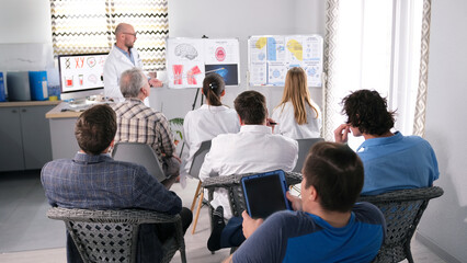 A group of interns and residents at a lecture on medicine. Several people are sitting on chairs in...