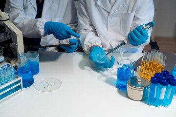 Medical or research scientist or doctor using looking at a test tube of clear solution in a lab or...