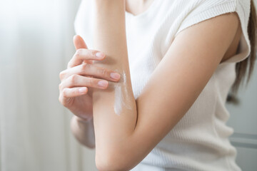 Health skin care, beauty asian young woman, girl  hand applying, putting moisturizer on her arm after shower bath at home. Skin body cream moisturizing lotion, routine in the morning.